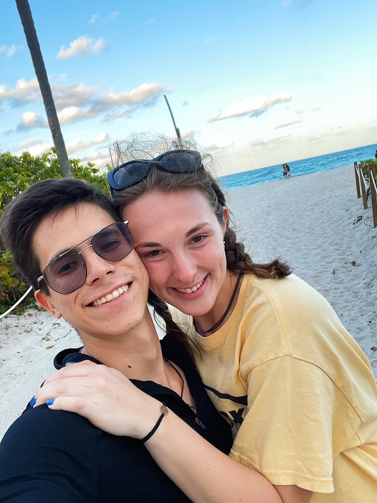 Jade and Juan smiling together on a sandy beach