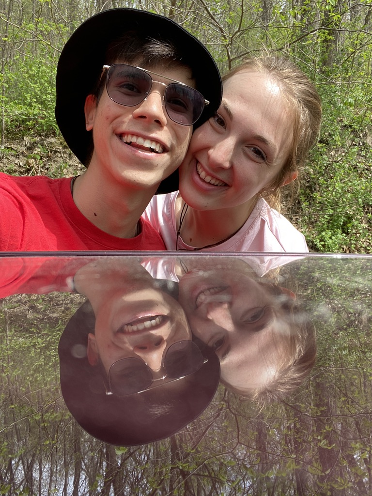 Jade and Juan smiling above their reflection on a car roof