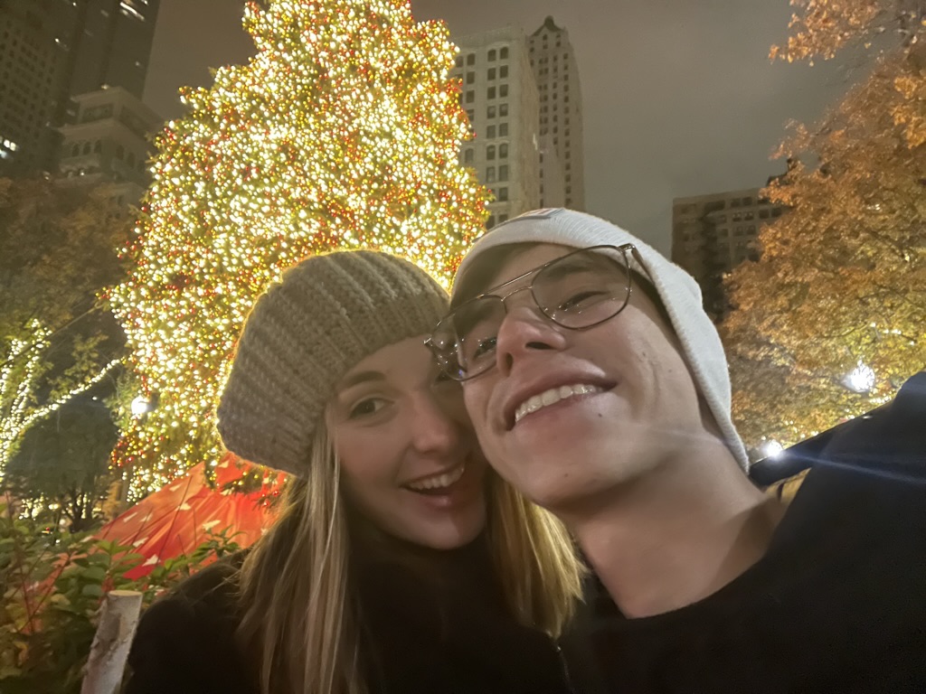 Jade and Juan smiling beneath a brightly lit Christmas tree