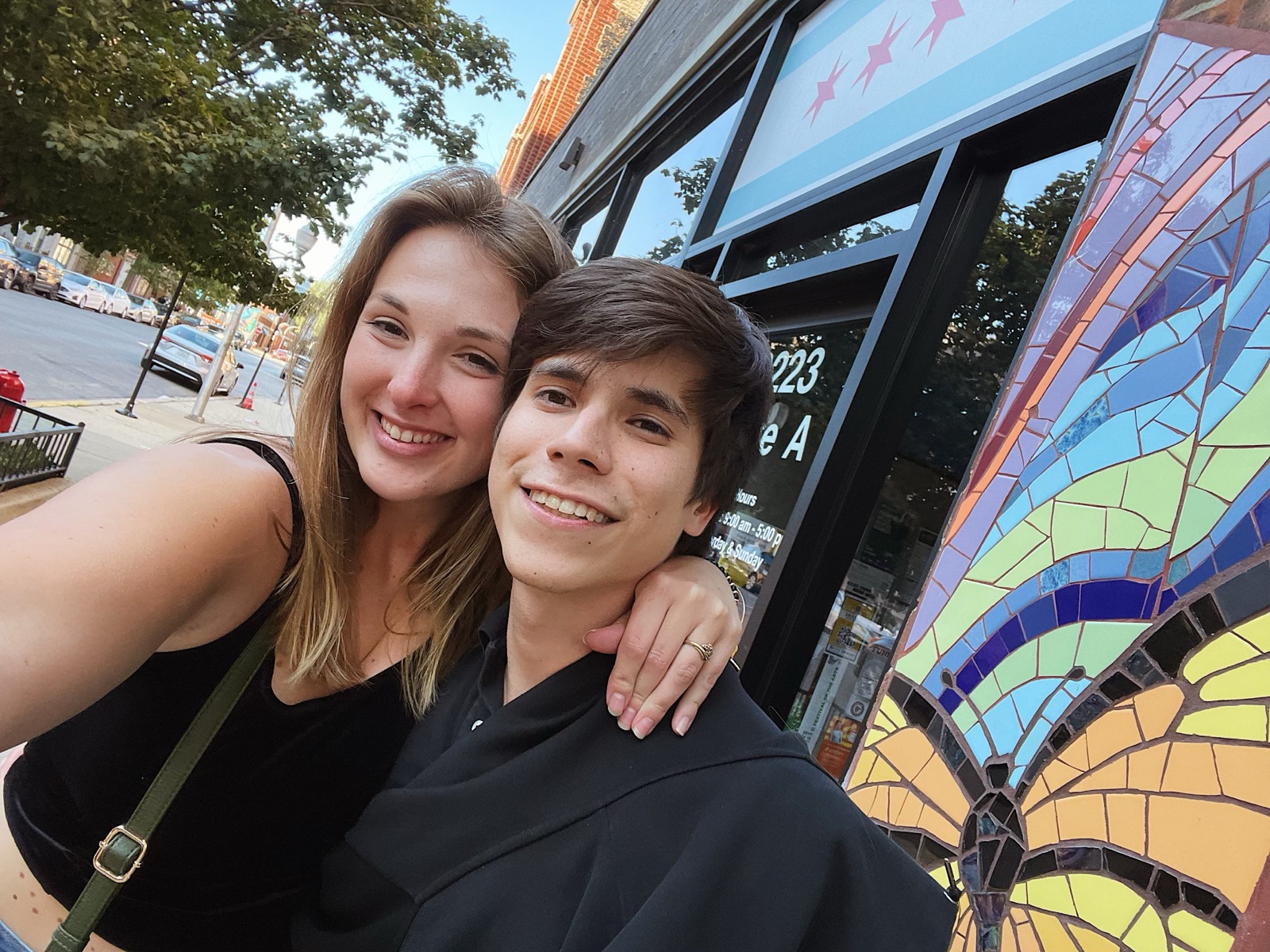 Jade and Juan smiling beside a colorful city mural