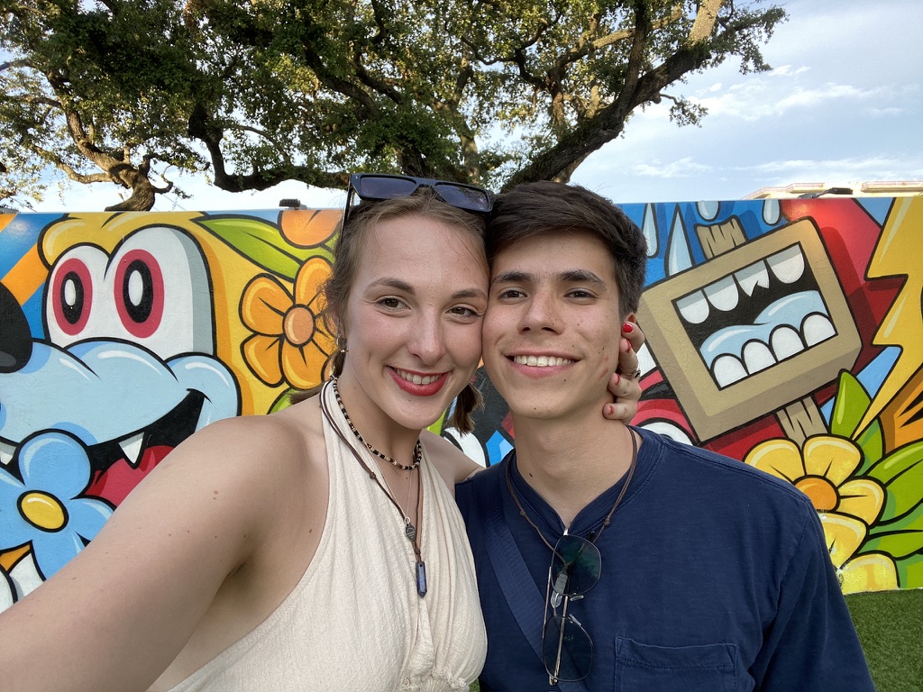 Jade and Juan smiling in front of a colorful mural