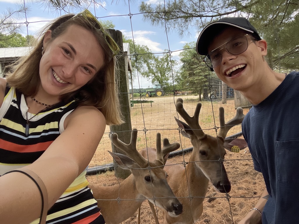 Jade and Juan smiling beside a group of deer