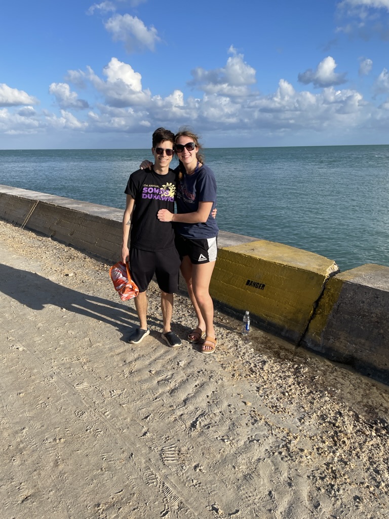 Jade and Juan standing together beside the ocean