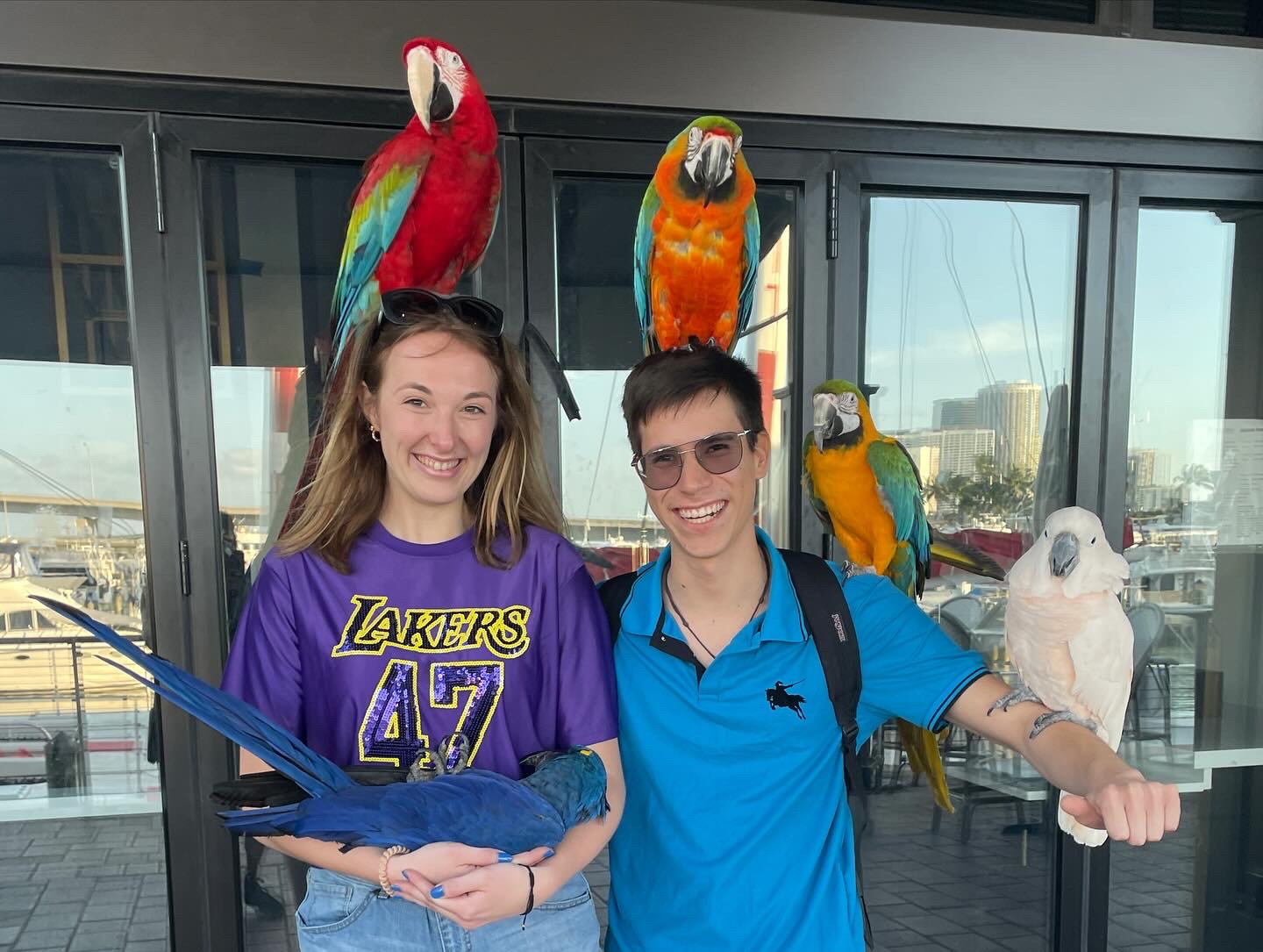 Jade and Juan smiling with colorful parrots