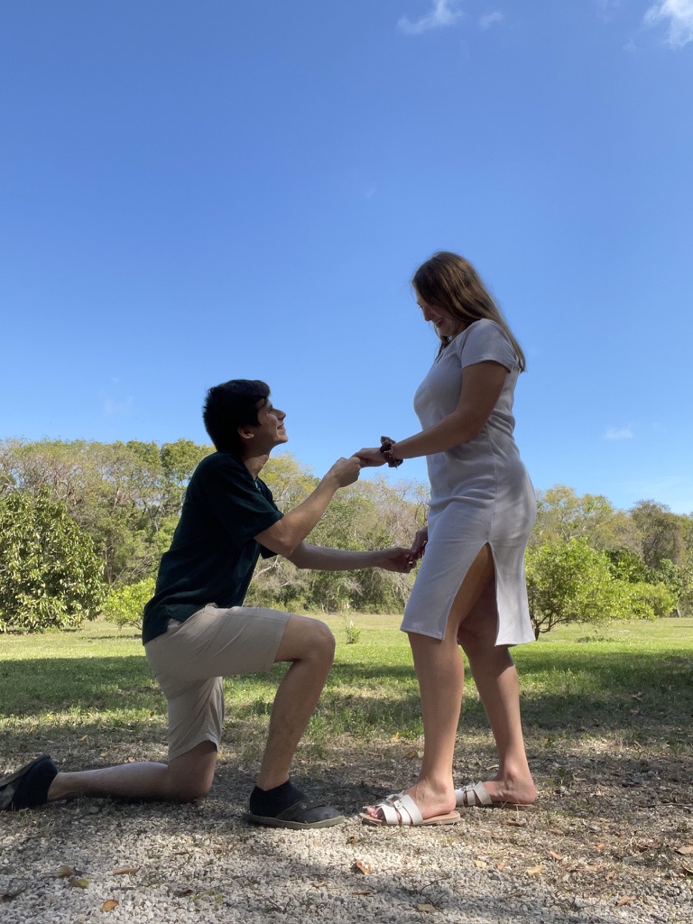Juan kneeling and holding Jade’s hand during their proposal